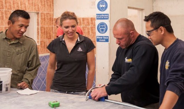 Instructor demonstrating how to cut tile edging to three students at Able Skills