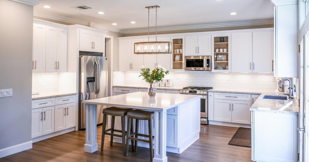 Neat, tidy and clean white fitted kitchen with stainless steel appliances and two stools at an island