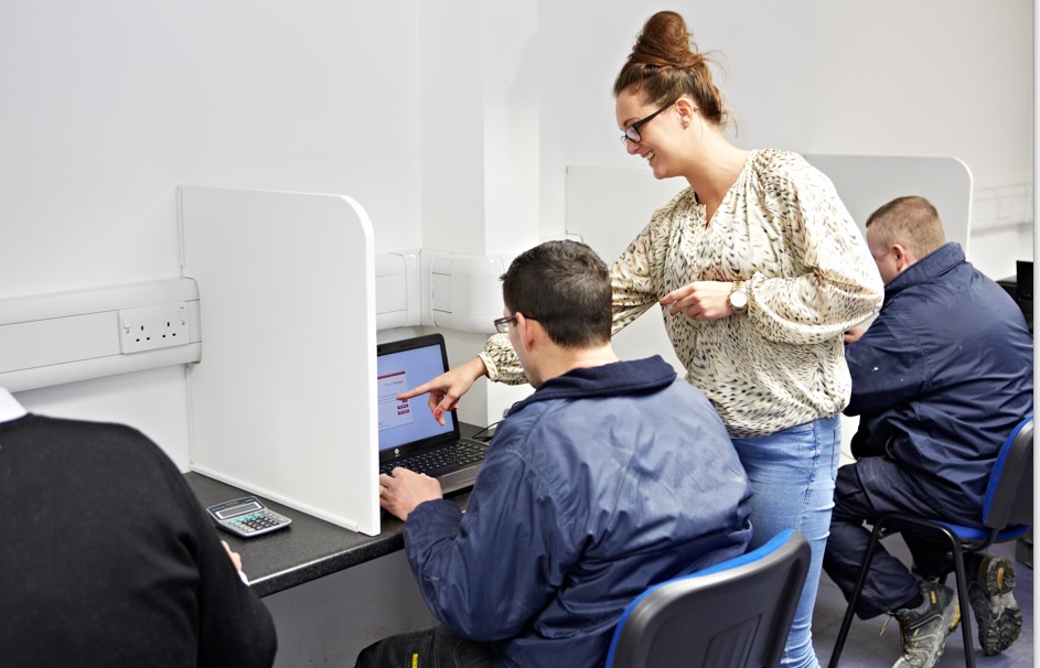 A staff member at Able Skills assists a student in an examination centre or classroom