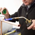 Person soldering copper pipes in the Able Skills construction training centre