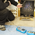 Gas engineer kneeling down testing a gas fire