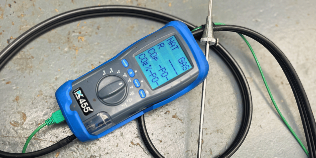 A gas analyser machine. A blue hand-held device with a digital display