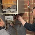 Image shows two people working on a gas appliance